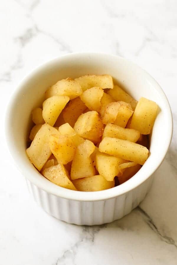stewed cinnamon apple pieces in a white bowl.