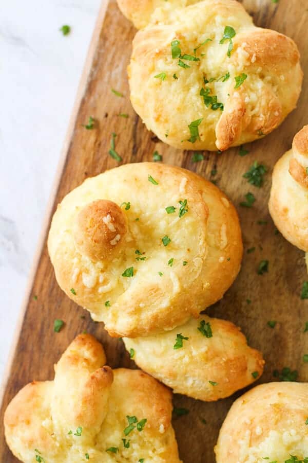 garlic knots on a wooden serving board.