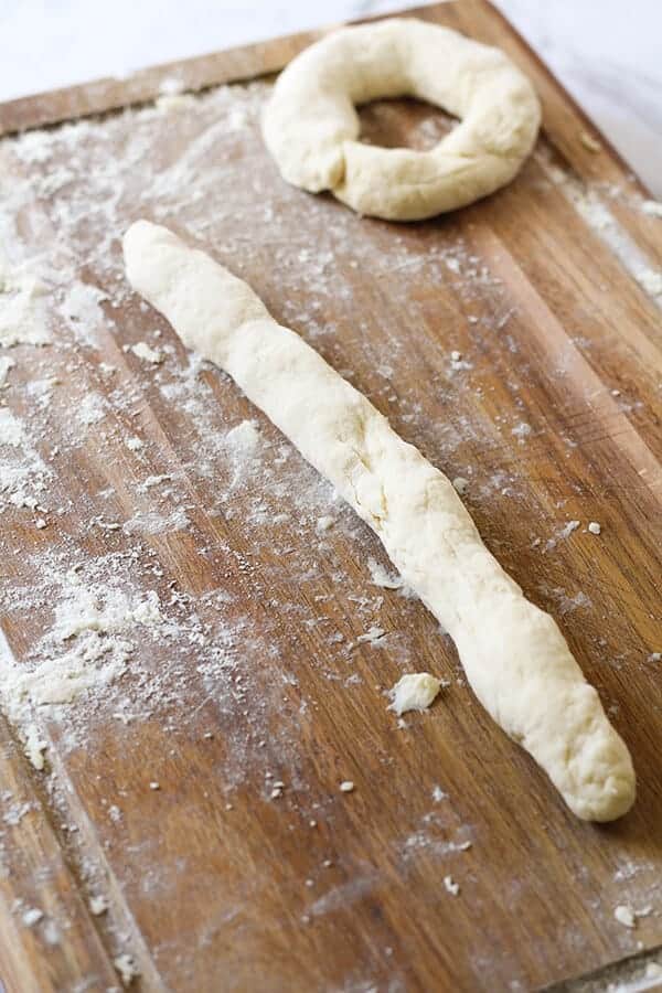 dough rolled out into a rope shape on a wooden board.