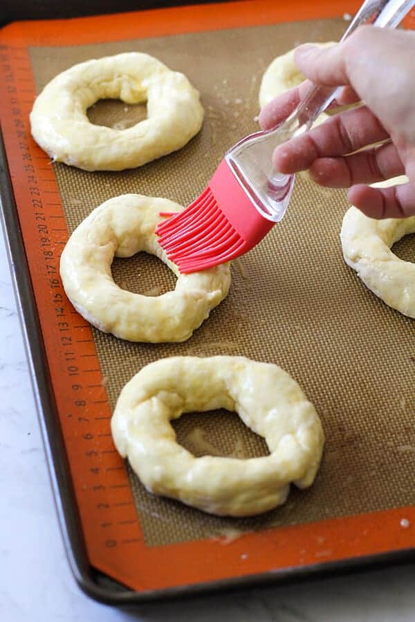 bagels being brushed with egg wash. 