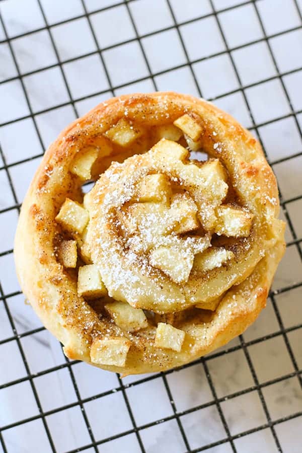 an apple cinnamon roll sitting on a wire rack.