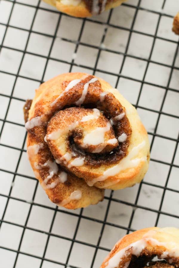 cinnamon roll on a wire rack covered with glaze.