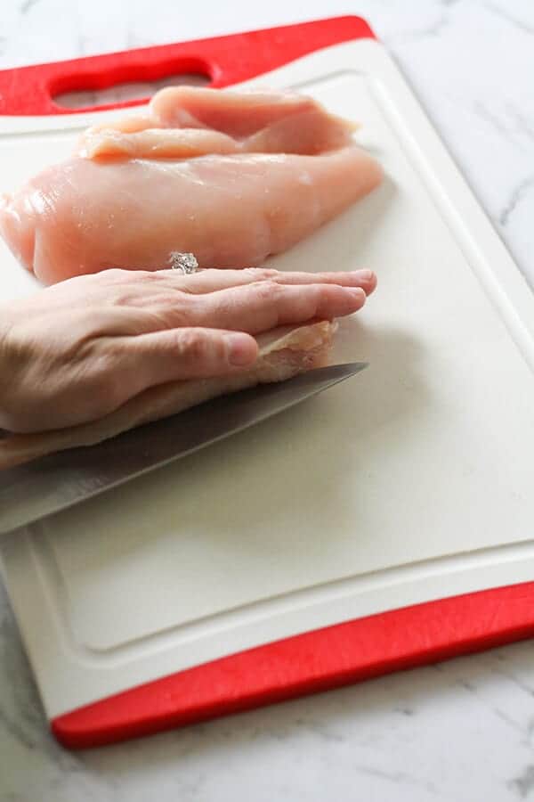 Chicken breast being cut in half.