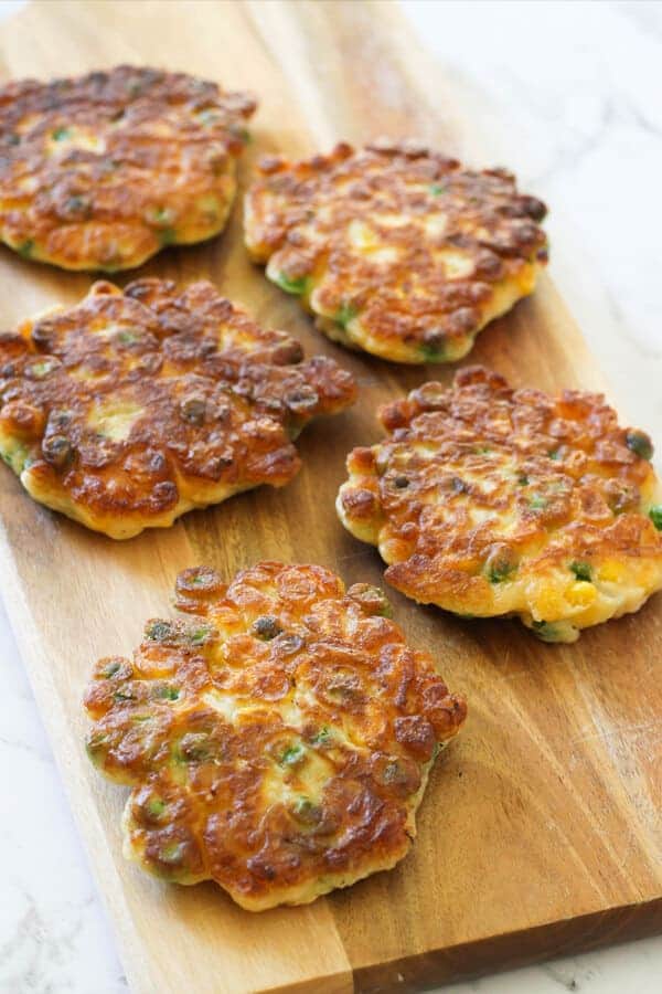 Pea & Sweet Corn Fritters on a wooden board.
