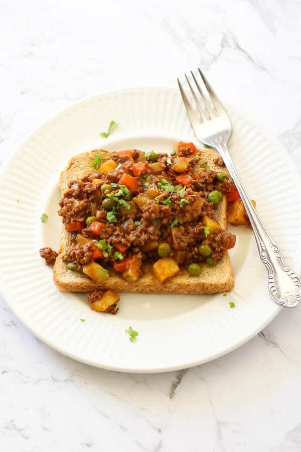 Savoury mince on top of a piece of toast on a white plate.