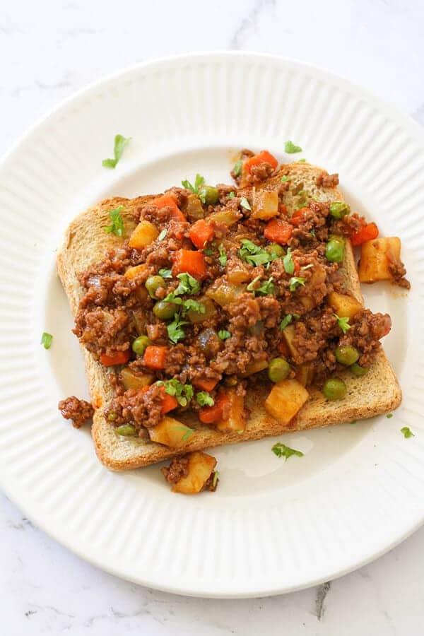 Savoury mince on top of a piece of toast on a white plate.