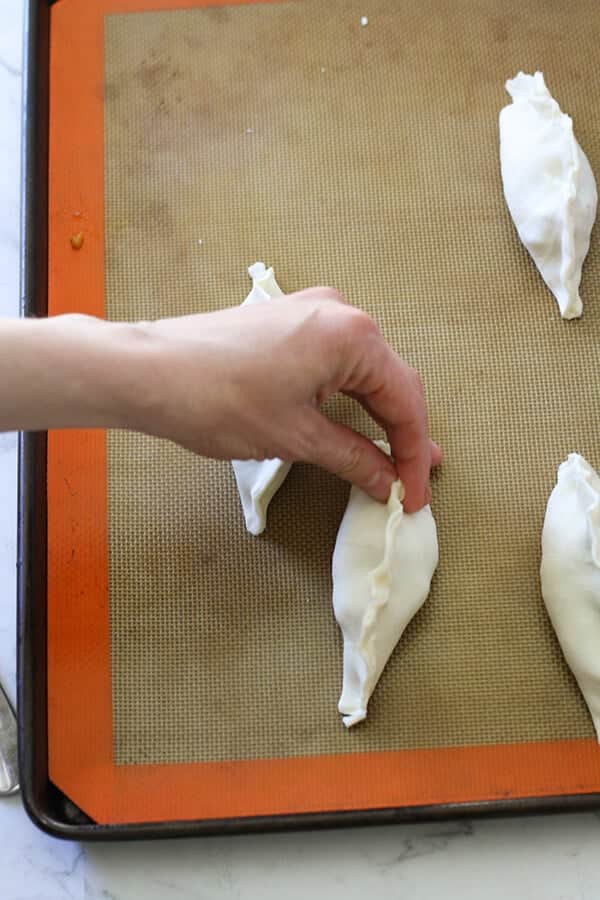 a hand crimping the edges of a pastie.