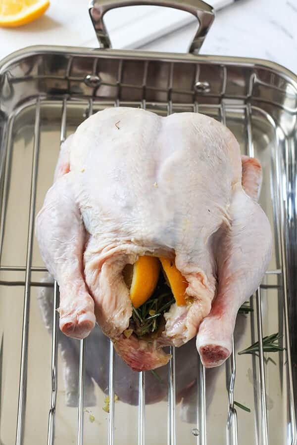 whole chicken stuffed with lemon wedges and rosemary ready for the oven.