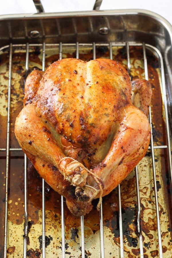 Whole roast chicken on a white plate.