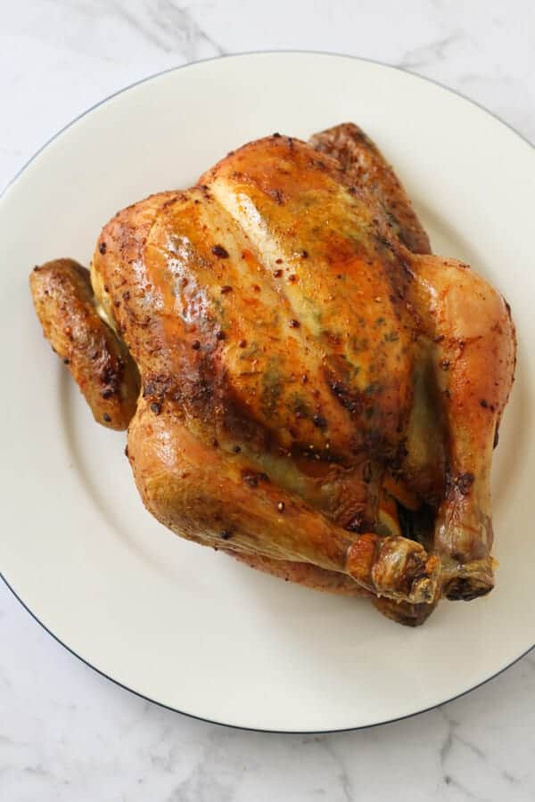 Whole roast chicken on a white plate.