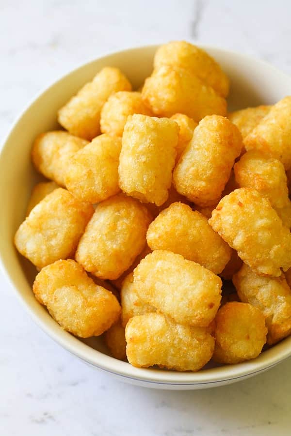 A white bowl filled with crispy tater tots.