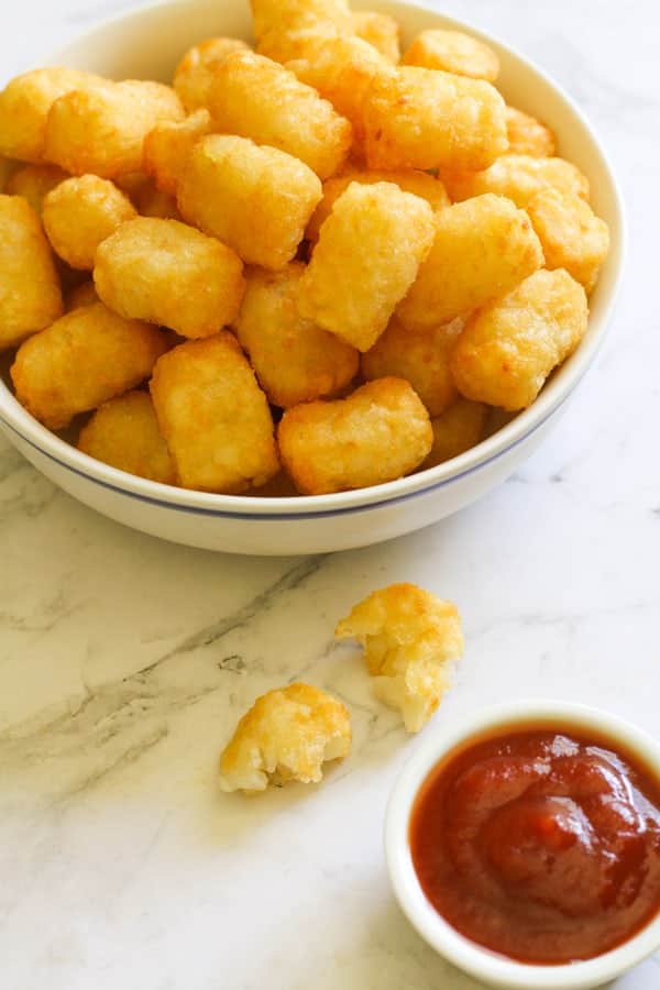 A white bowl filled with crispy tater tots.