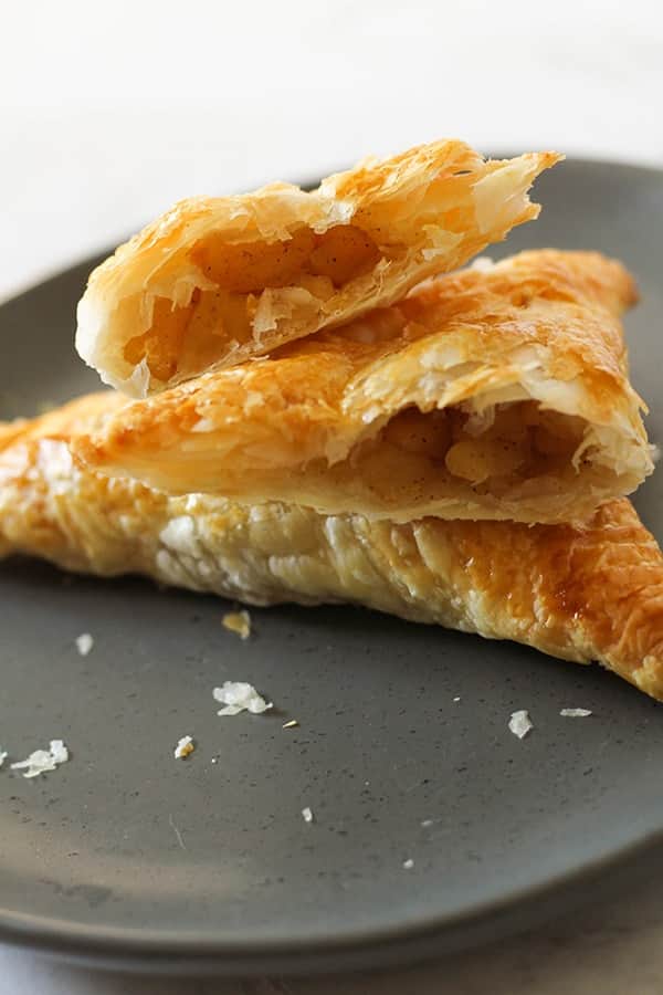 apple turnover broken in half on a grey plate.
