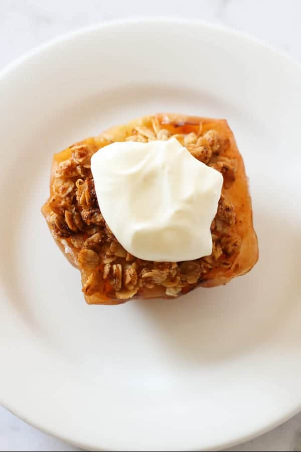baked apple topped with ice cream on a white plate.