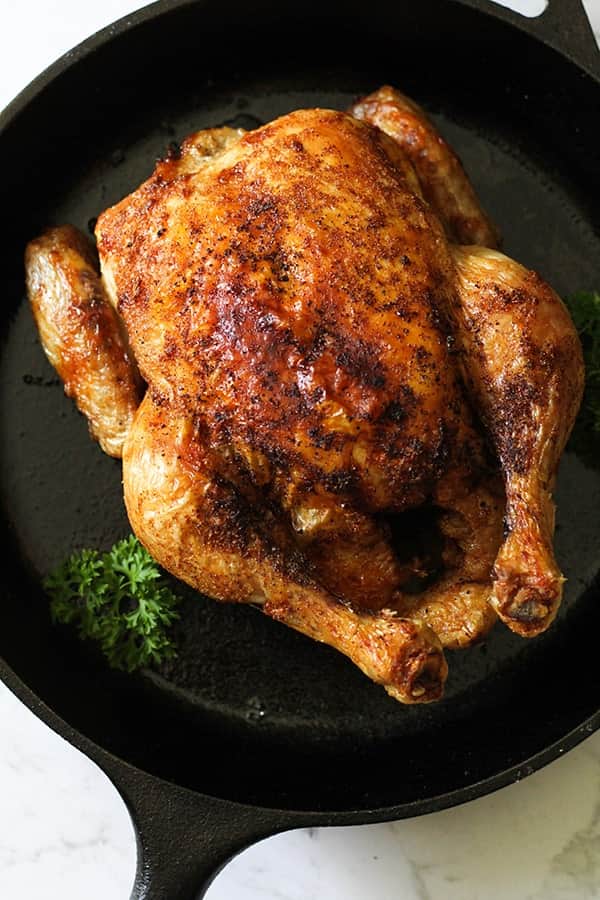 Whole roast chicken sitting in air fryer basket.