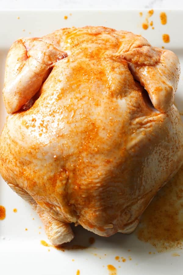 chicken sitting on a large plate rubbed in seasoning.