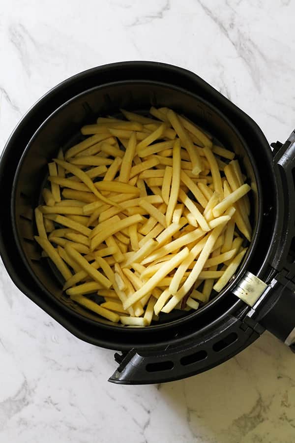 frozen french fries in an air fryer basket. 