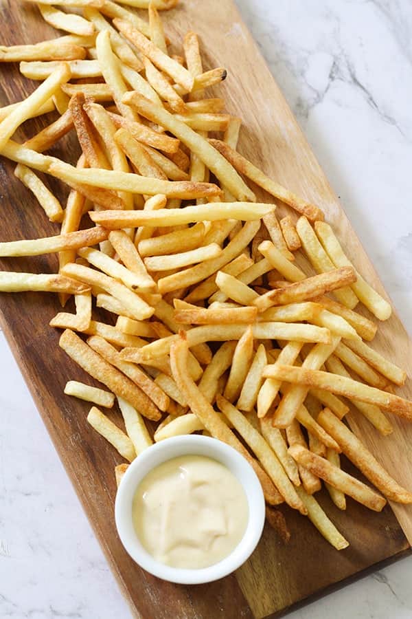 French fries on a wooden serving board.
