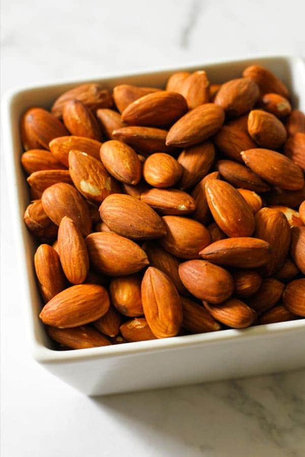 Roasted almonds in a white square serving bowl.