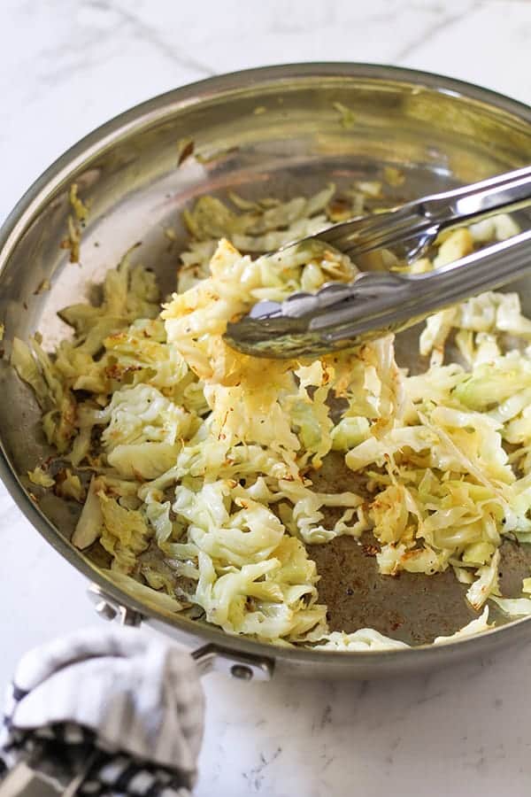 sauteed cabbage in a stainless steel frying pan.