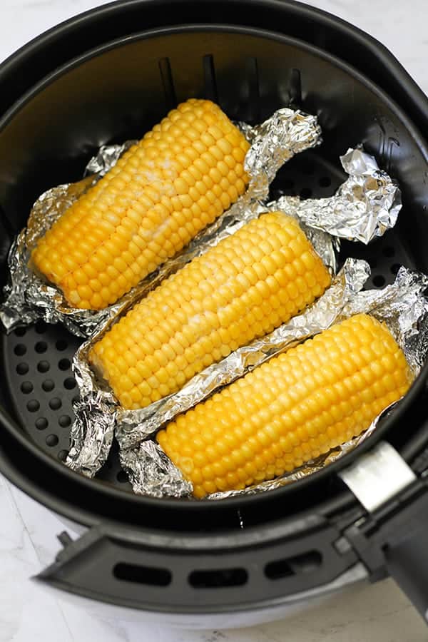 corn ears in an air fryer basket.