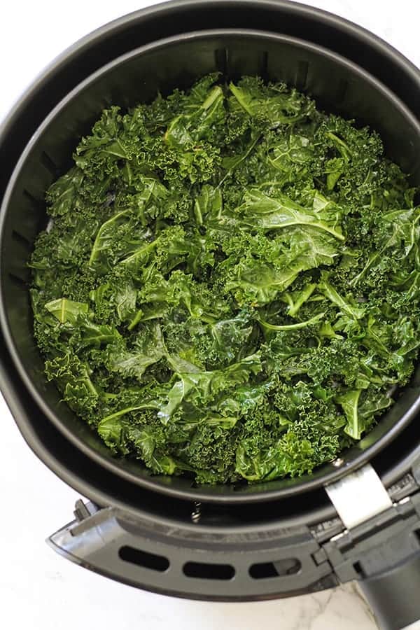 kale leaves in air fryer basket.