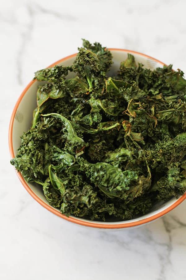 sweet and salty kale chips in a white bowl.