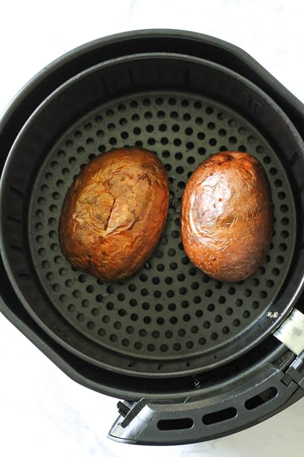 baked potatoes in an air fryer basket.