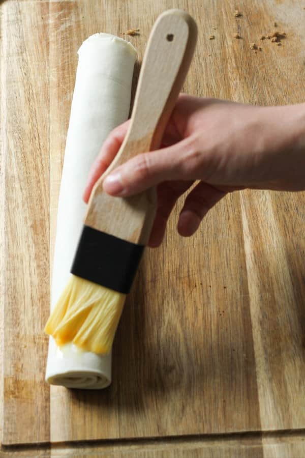 rolled pastry being brushed with eggs.