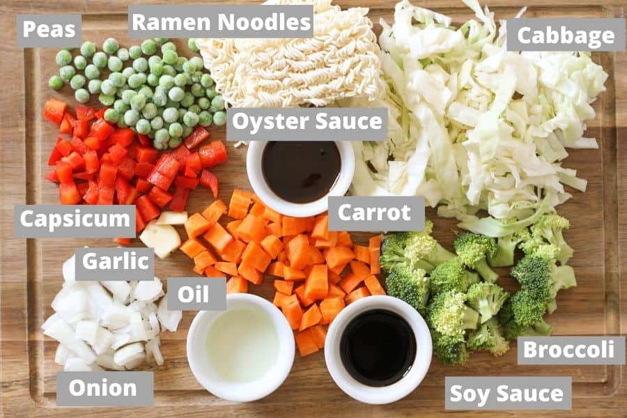ingredients for vegetable stir fry with noodles on a wooden board.