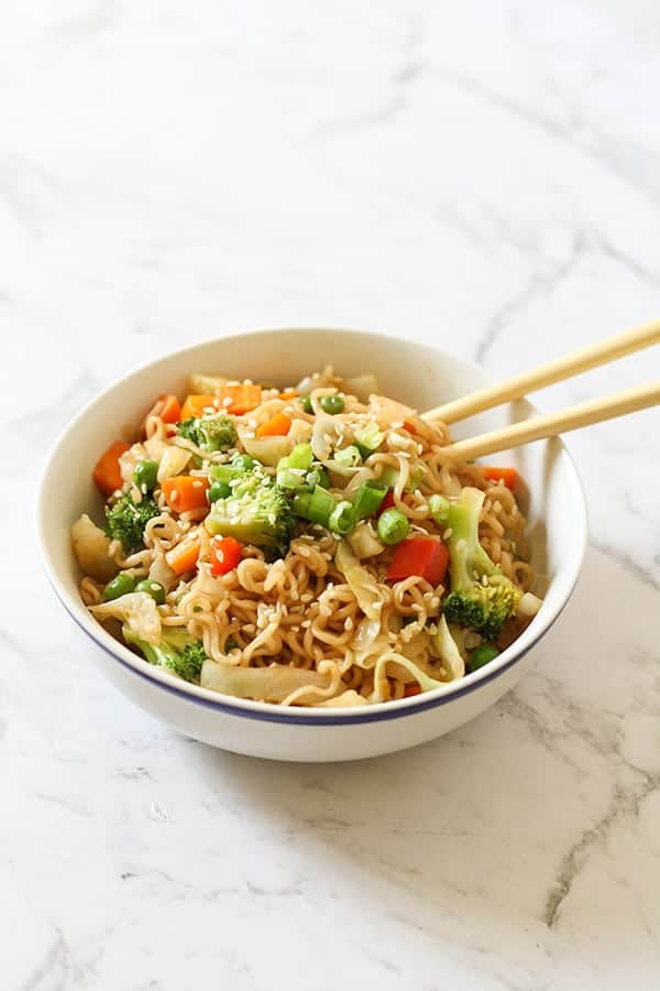 vegetable stir fry with noodles in a white bowl with chopsticks.