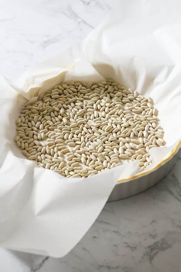quiche crust covered in baking paper and pie weights. 