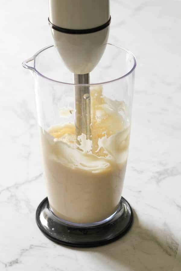 mayonnaise being made in a jar with an immersion blender.