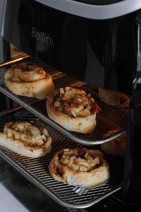 apple cinnamon rolls in an air fryer cooking.