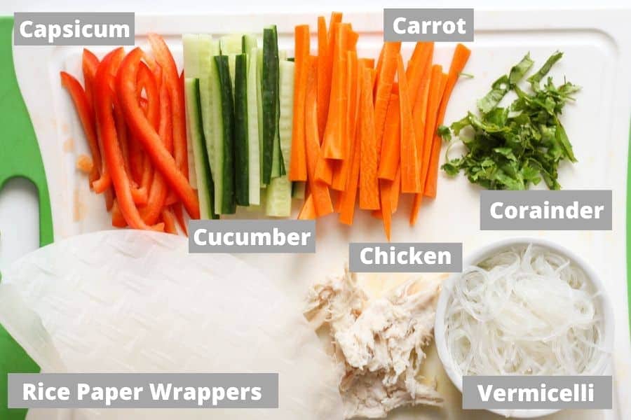 ingredients for chicken rice paper rolls on a cutting board.