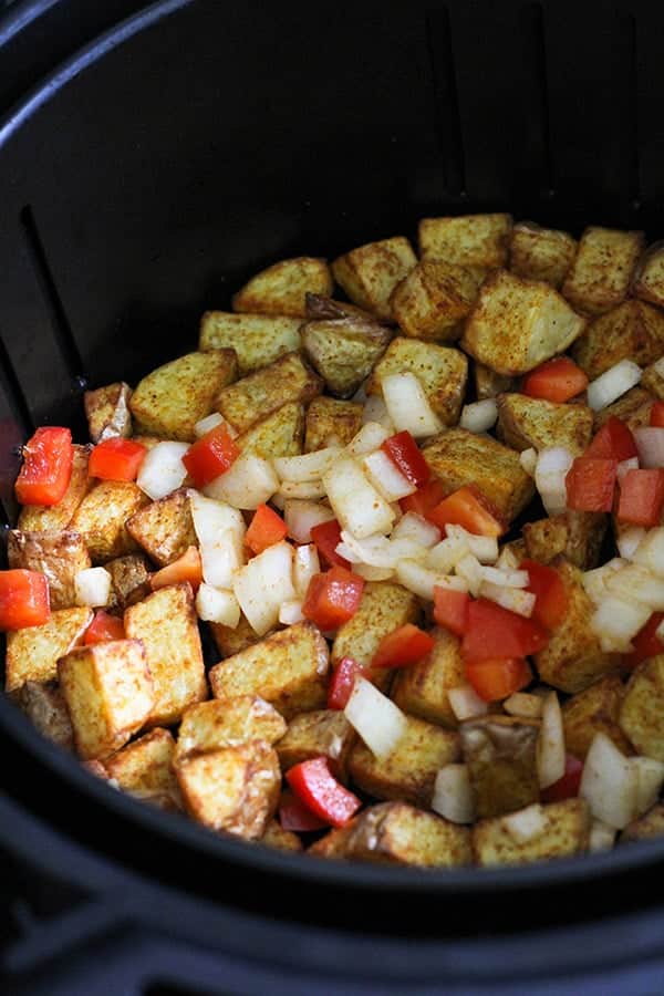 potatoes, capsicum and onion in an air fryer basket.