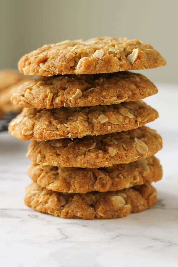 chewy anzac biscuits stacked on top of each other on a marble board.