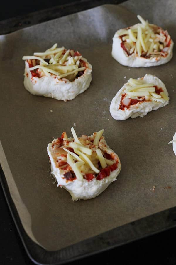 uncooked pizza rolls on a baking tray.