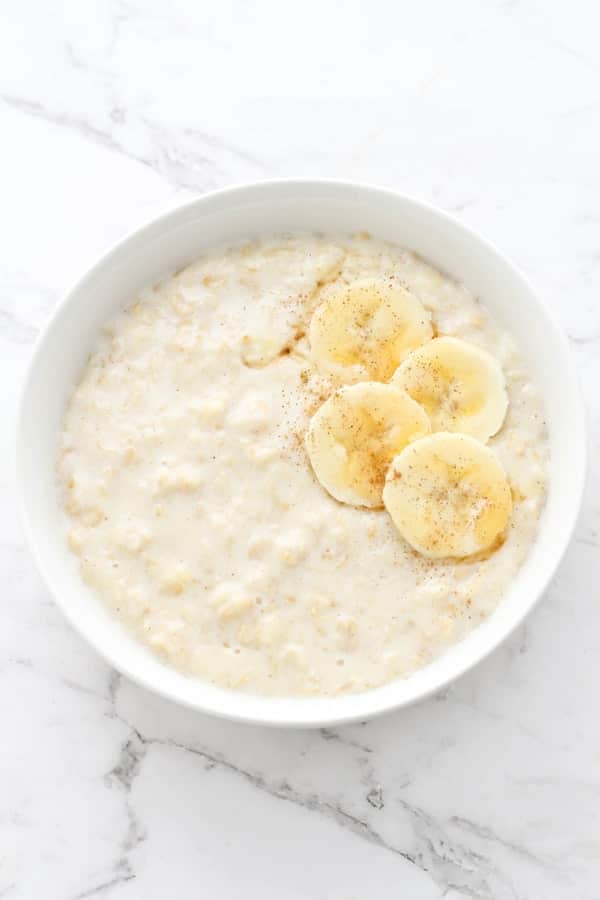 porridge in a white bowl topped with banana slices.