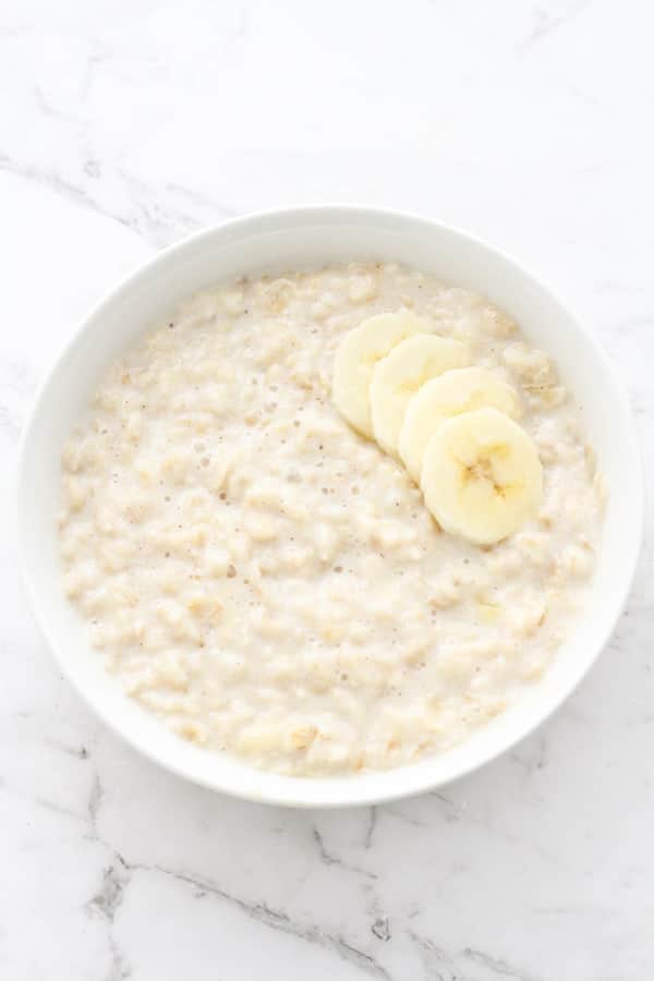 porridge in a white bowl topped with banana slices.