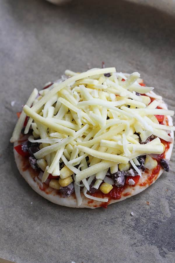 pizza base covered in cheese on a baking tray.