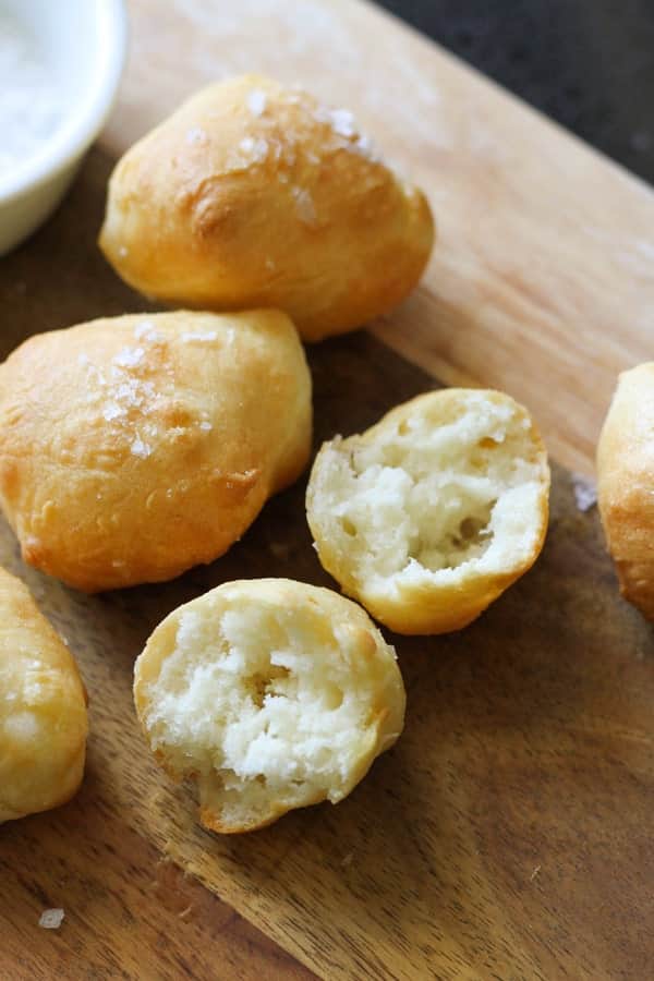 a pretzel bite split in half on a wooden serving board.