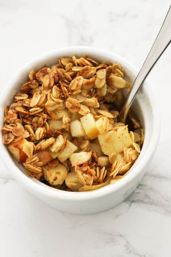 apple crisp in a white ramekin with a spoon.