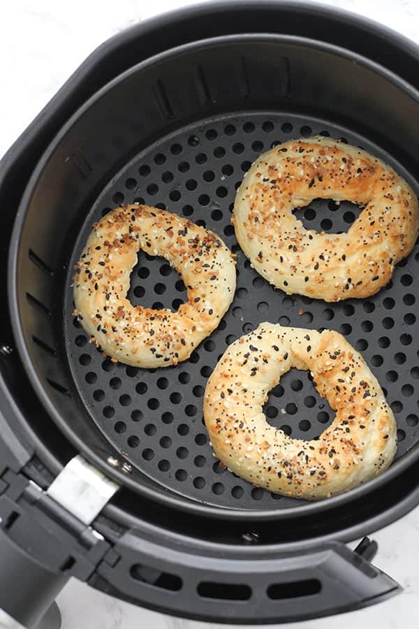 cooked bagels in an air fryer basket.