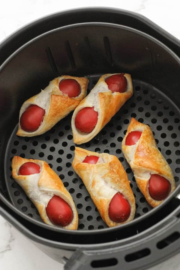 pigs in a blanket in an air fryer basket.