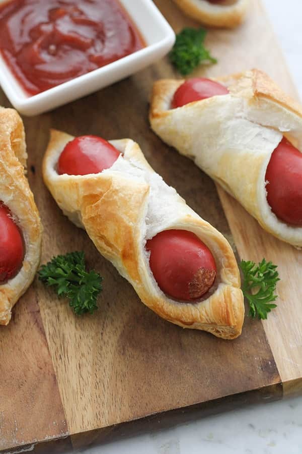 pigs in a blanket on a wooden serving board.