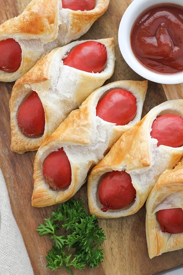 pigs in a blanket on a wooden serving board.
