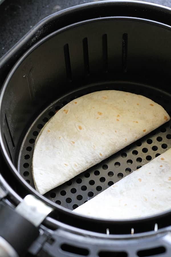quesadillas in an air fryer basket ready to be cooked.