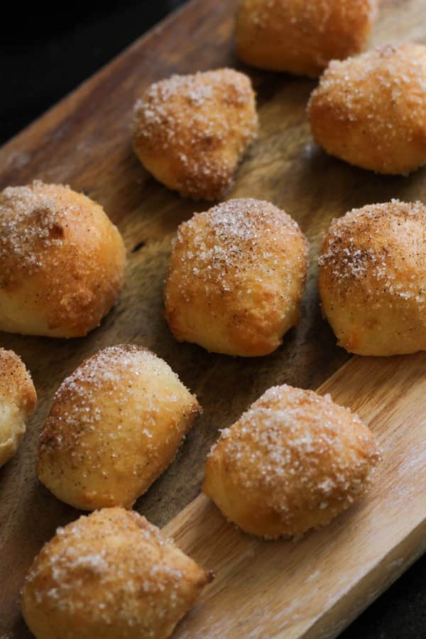 pretzel bites covered in cinnamon sugar on a wooden board.