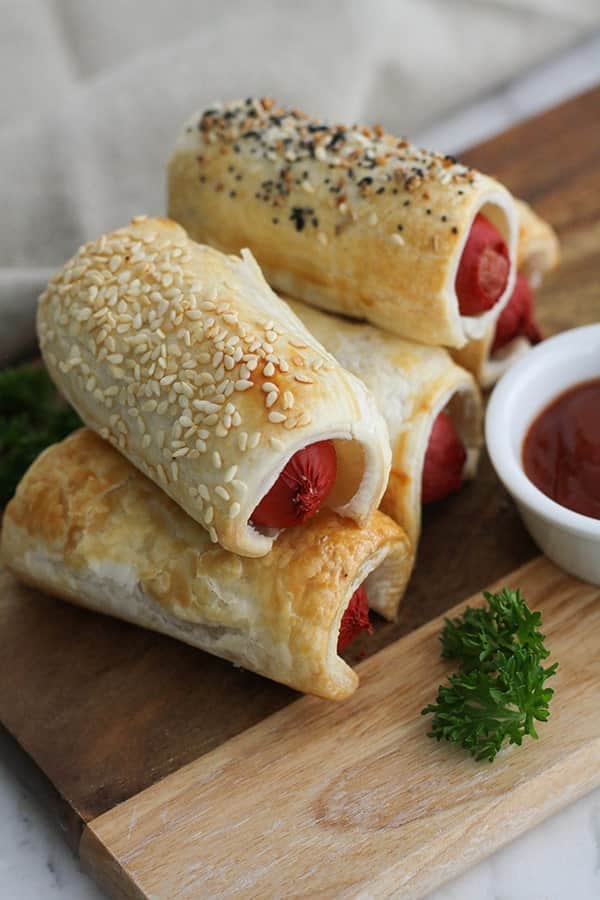 puffy dogs stacked on a wooden serving board.